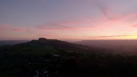 Aerial-tracking-slowly-sideways-of-a-glorious-red-sunset-over-the-green-devon-fields-in-and-around-the-Blackdown-Hills