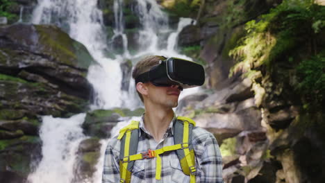 a person in a virtual reality helmet against the backdrop of a beautiful waterfall