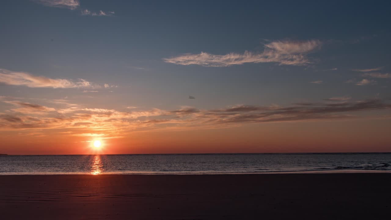 Time lapse shot  of sunset above calm waves at a beach, on Langeoog island, in North Germany