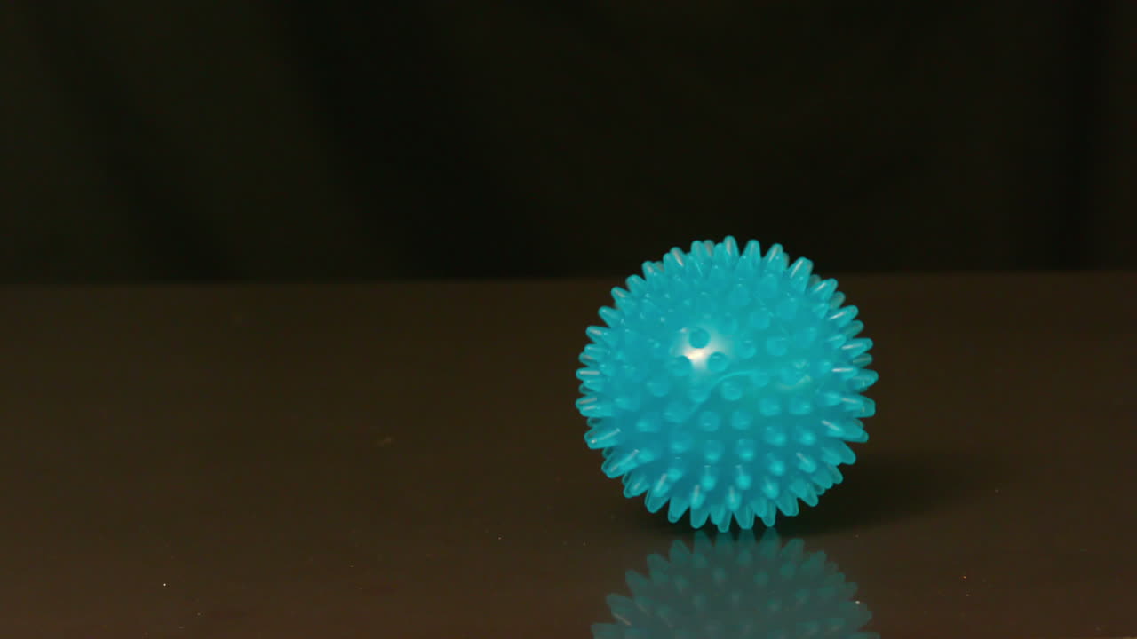Pelota de masaje girando sobre una superficie negra