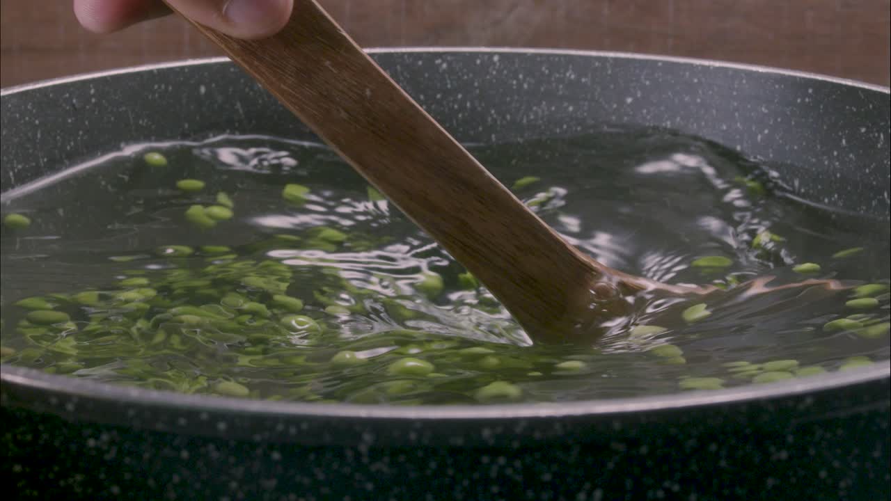 냄비에 완두콩 요리, 나무 주걱으로 물 흔들기