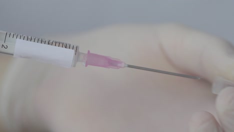 medical syringe uncapped by hand wearing white gloves, close up shot