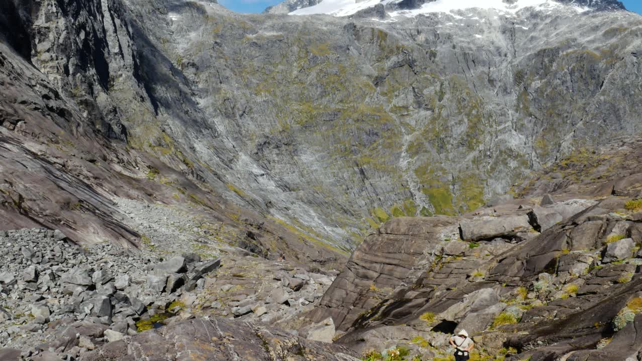 Aerial top down shot of exhausted hiker climbing and hiking up steep rocky mountains during sunlight - Gertrude Saddle Walk,NZ