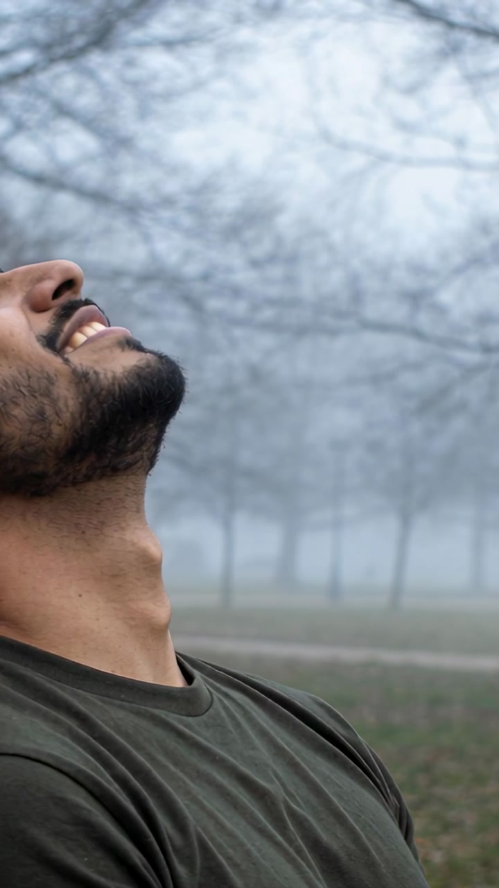Vertical video: Man tilting head back after noticing foggy sky, wellness graphics tracing breath