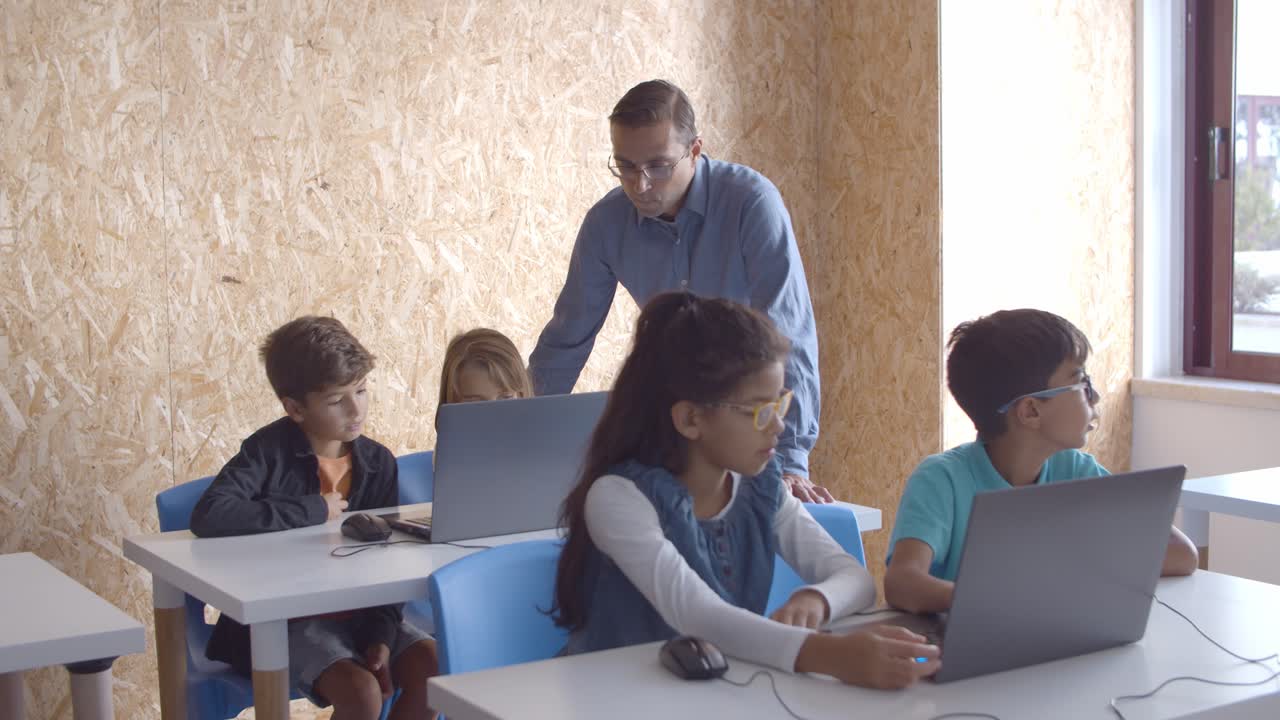 maestro de pie en los alumnos con computadoras portátiles en la clase