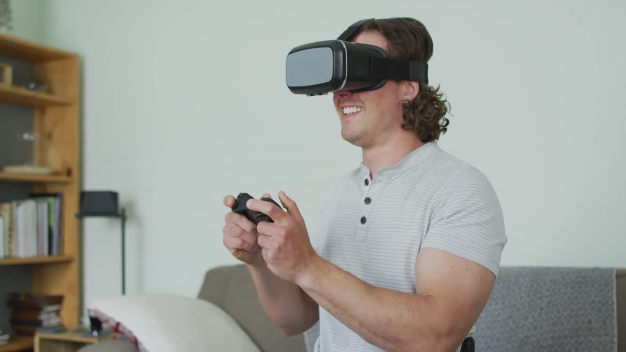 Uomo caucasico felice che indossa un visore VR e tiene in mano un gamepad in salotto.