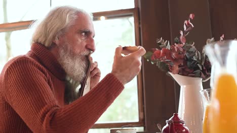 hombre de edad avanzada comiendo tostadas de tomate en un restaurante