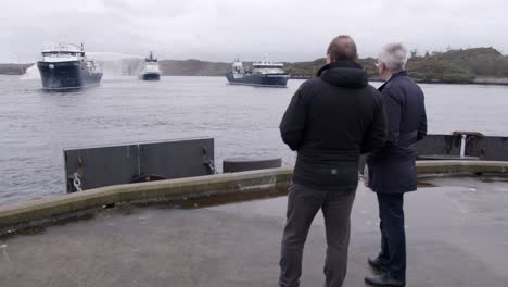 Zeitlupenaufnahme-Eines-Schiffes,-Das-Mit-Seiner-Wasserkanone-Wasser-Spritzt,-Während-Zwei-Personen-Vom-Pier-Aus-Zuschauen