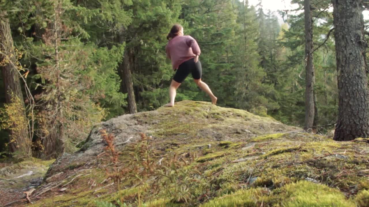 mujer joven practica yoga y danza al amanecer en un bosque de pinos