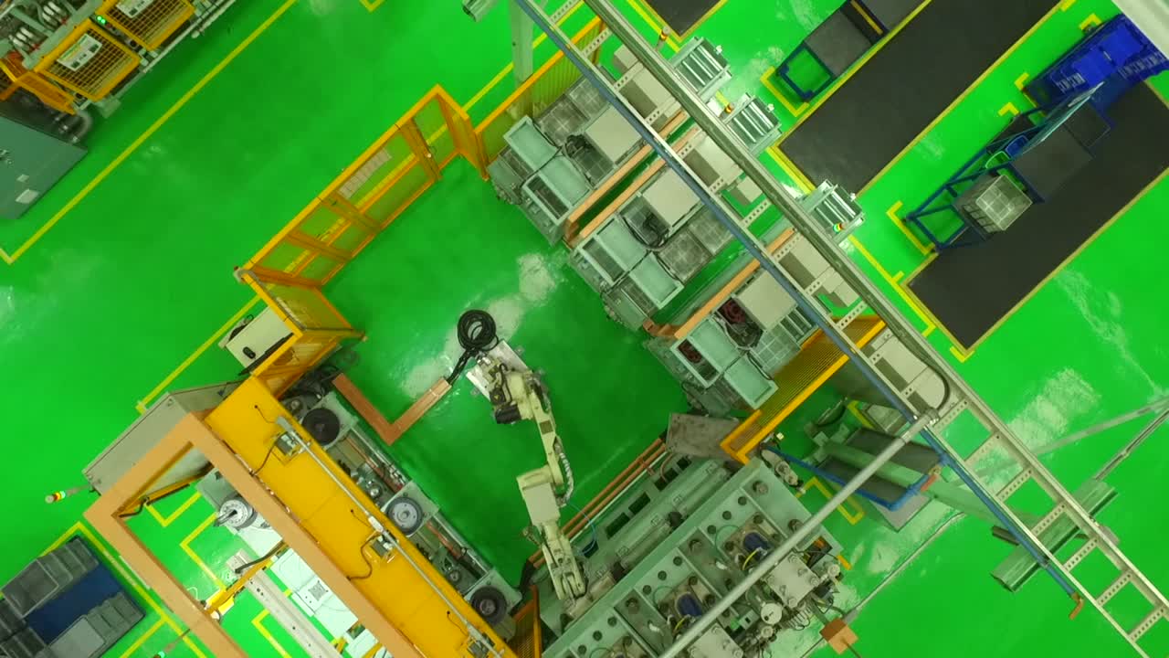 Top down view of industrial robotic arm working in bright green modern factory