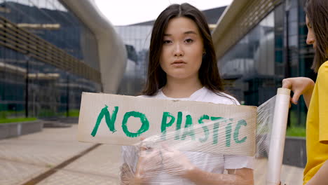 primo piano della donna che avvolge una ragazza con pellicola di plastica