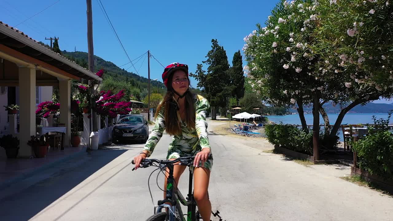 Close up drone shot young woman riding her bike on the coast.