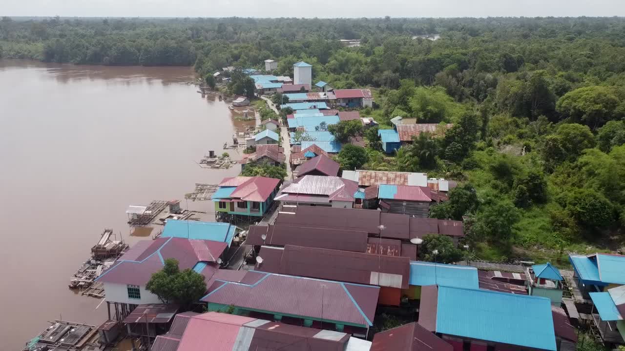 zoom-out de drones de un pequeño pueblo tropical, a medida que se aleja, revela la jungla circundante y las casas cerca del río