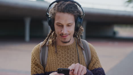 portrait happy young man student using smartphone enjoying browsing online reading text messages wearing headphones listening to music