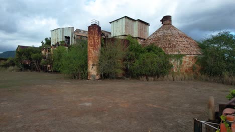 zoom in over derelict truck to overgrown koloa sugar mill in hawaii, drone