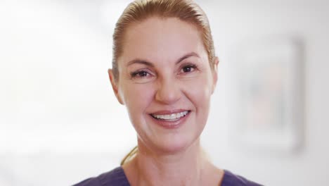 Video-portrait-of-happy-caucasian-female-doctor-smiling-in-hospital,-with-copy-space