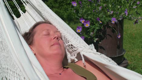mujer de mediana edad relajada pacíficamente en una hamaca con el sol en su rostro