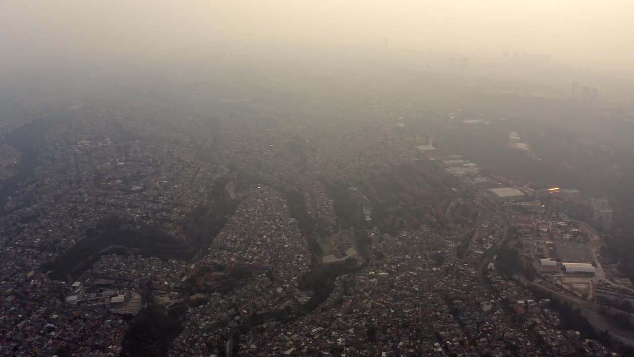 Aerial shot of big urban settlements in ravines in a very polluted day in Mexico City