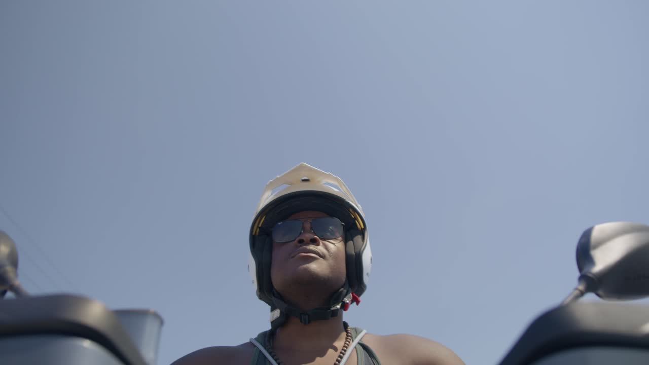 hombre negro conduciendo una motocicleta en la calle, policía de playa, aplicación de la ley, pobreza, 4k | mirando a su alrededor, tembloroso, carretera, viajes, árboles