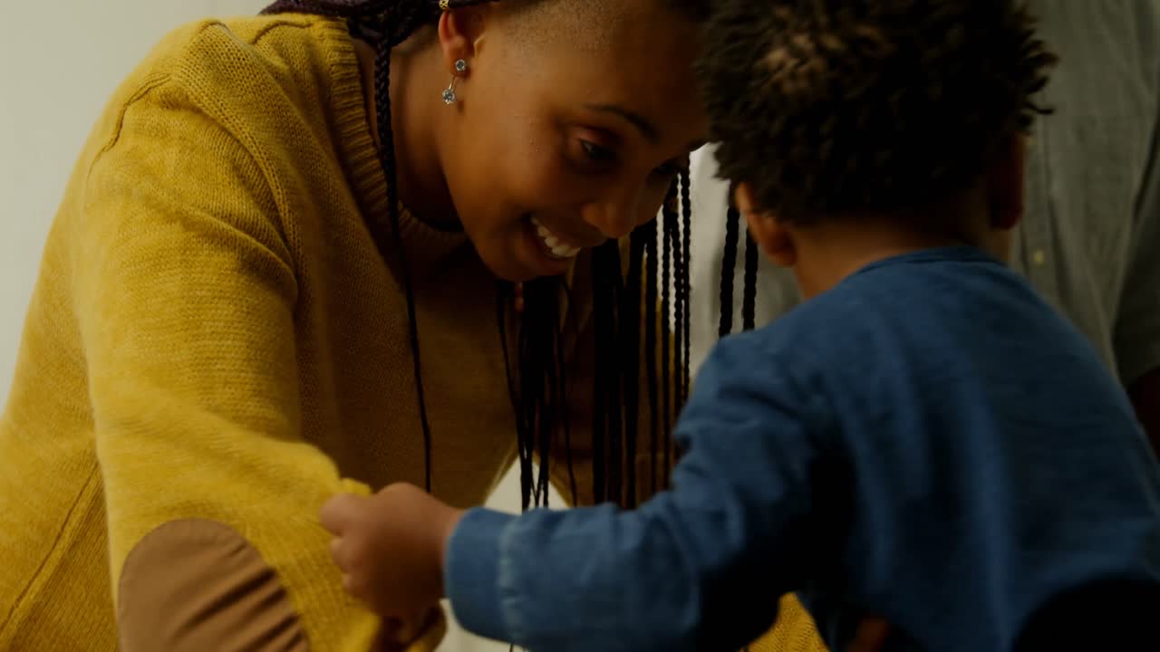 vista lateral de una joven madre negra jugando con su hijo en un cómodo hogar 4k