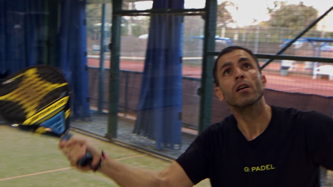 el hombre golpea una pelota alta sobre la red en un partido de pádel - cámara lenta