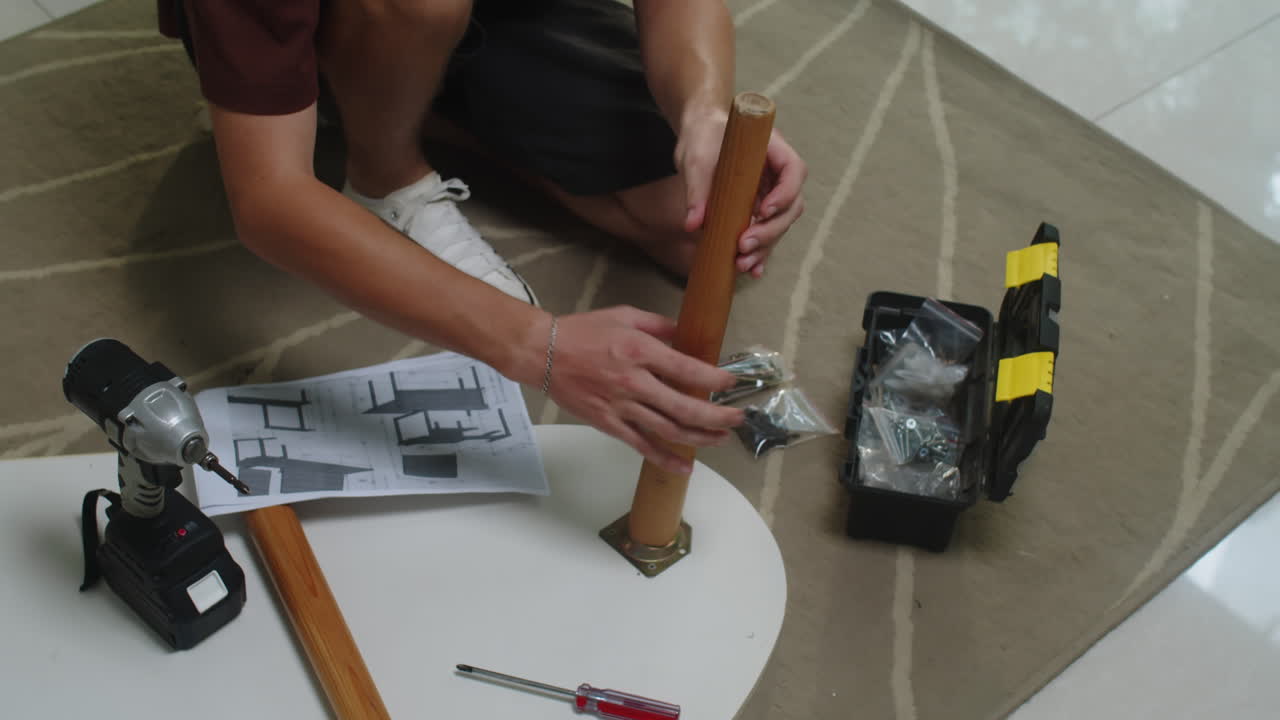 Man Screwing Leg to Metal Fittings on Coffee Table