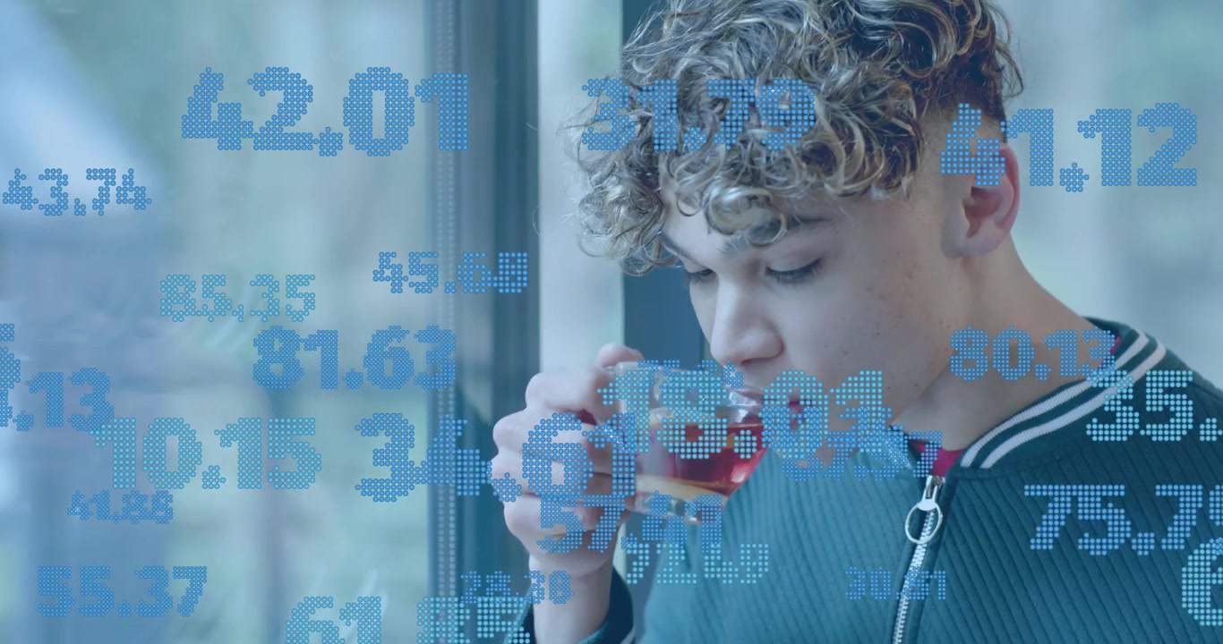 Man at window following floating tech data overlay, lifting glass cup to lips savoring tea warmth