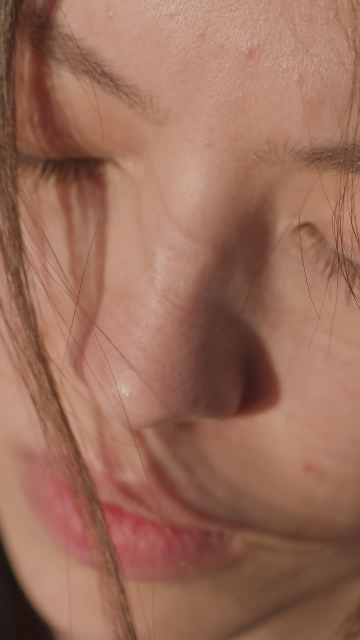 primer plano del rostro de una chica con los ojos cerrados, su expresión profundamente infeliz y triste. su cabello cubre parcialmente su cara, añadiendo a la sensación de melancolía e introspección