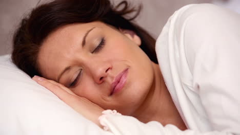 una bonita morena acostada en la cama durmiendo