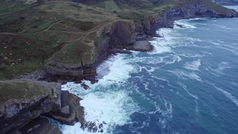 Isla,-Una-Isla-Deslumbrante-En-Cantabria,-Se-Cubre-De-Verde,-Y-El-Mar-Golpea-Violentamente-Contra-Su-Orilla