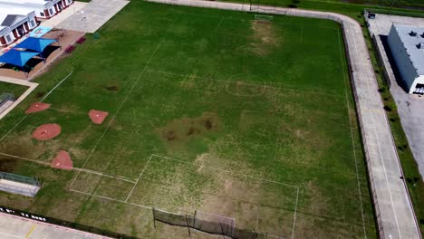 An aerial view of a worn baseball field beside a soccer field