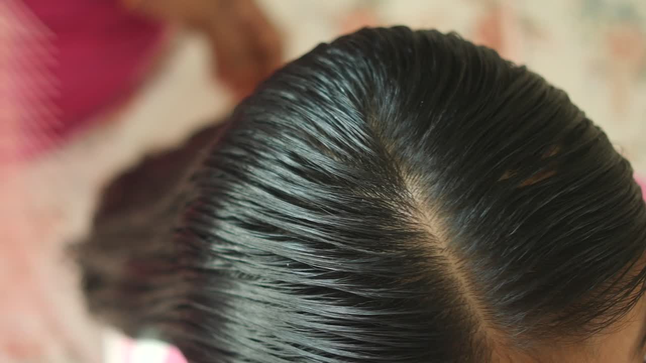 Close-up of dark hair being parted and styled