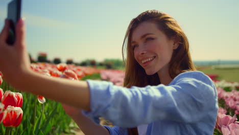 Young-woman-making-selfie-in-beautiful-flower-garden.-Girl-smiling-in-smartphone