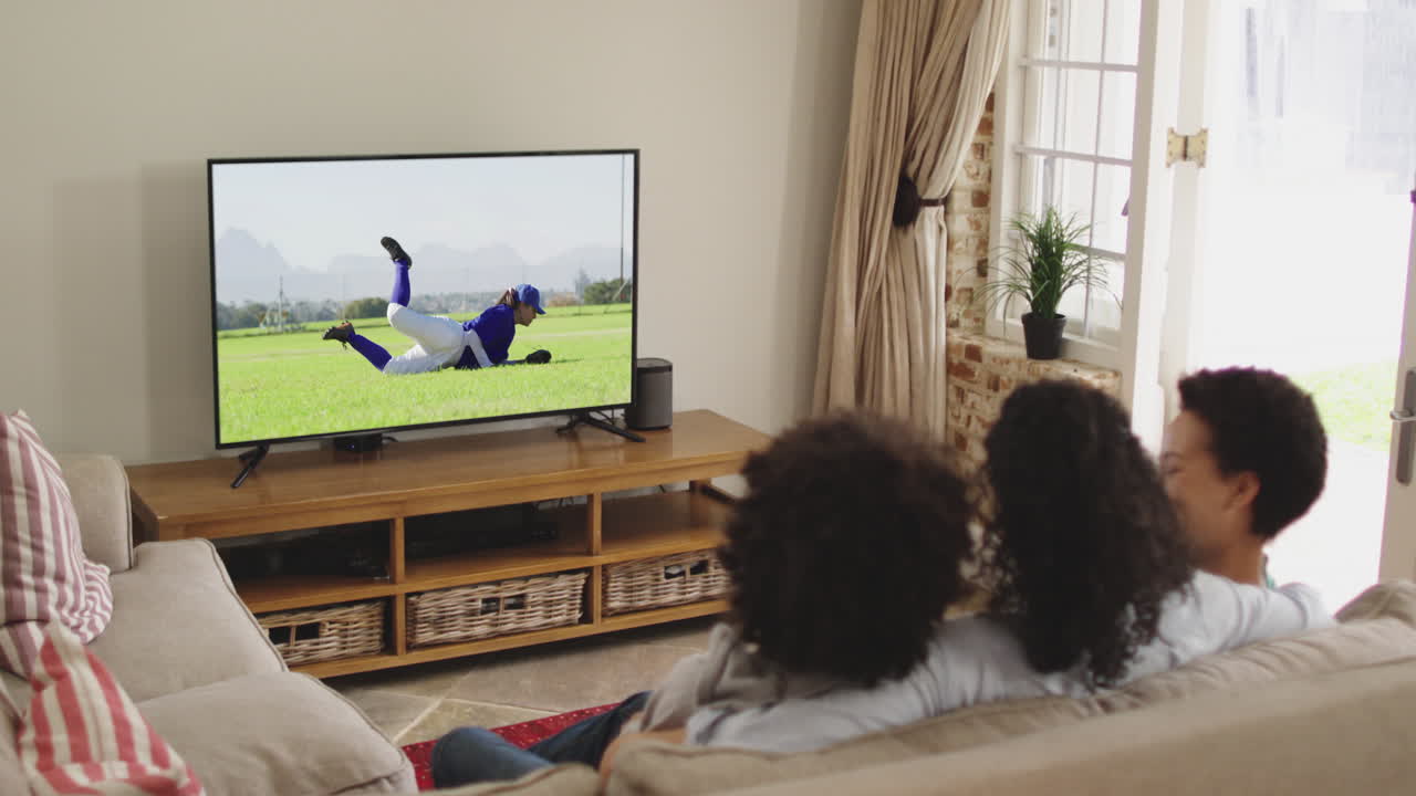 Famiglia felice seduta a casa insieme che guarda una partita di baseball in TV