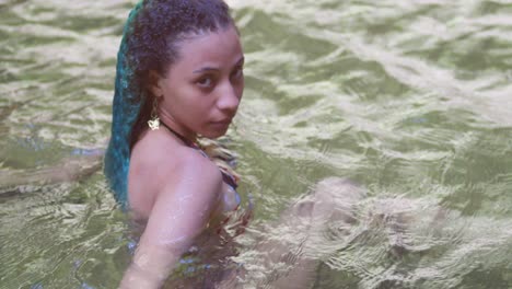 a girl lay in a river with green curly hair on a tropical island in the caribbean