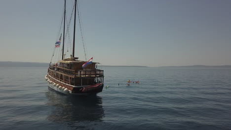 orbiting aerial of live-aboard tour ship in adriatic sea flying flags