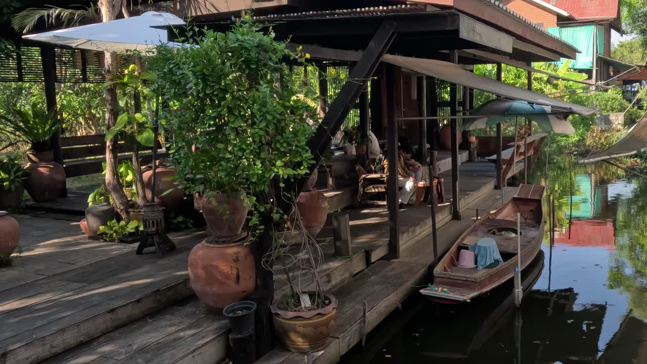 A wooden dock adorned with potted plants and a canoe moored alongside in a tranquil setting.