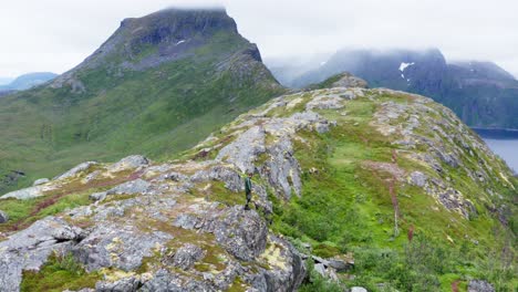 excursionista masculino de pie en un terreno rocoso cerca del pico de la montaña segla en la isla senja, noruega
