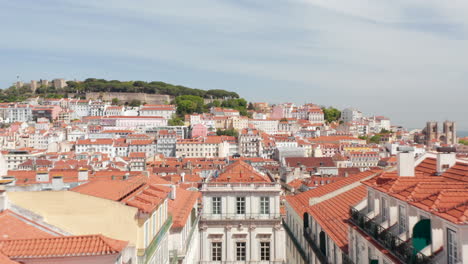 Aerial-dolly-in-view-of-colorful-traditional-European-houses-with-orange-rooftops-and-old-castle-on-the-hill-in-Lisbon-city-center