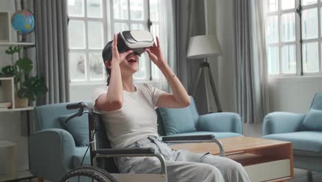 mujer asiática sentada en una silla de ruedas mientras usa gafas de realidad virtual en casa