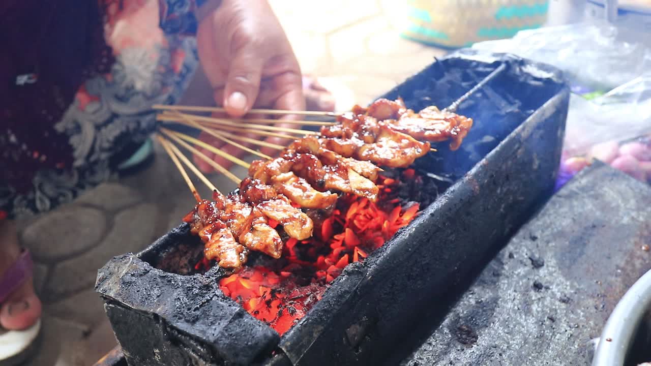 Satay-katukauppias grillaamassa satayta hiiligrillillä, epätarkka ja kohiseva otos