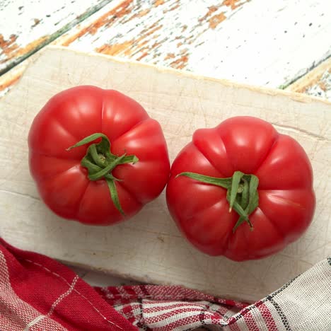 Two-fresh-eco-tomatoes-placed-on-white-wooden-cutting-board--Healthy-food-concept