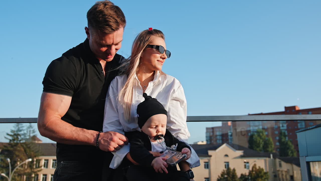 Beautiful Caucasian couple with their adorable newborn. Happy family of three outdoors. Low angle view.