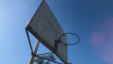 Rusty-basketball-hoop-on-inner-city-basketball-court-no-net-4K