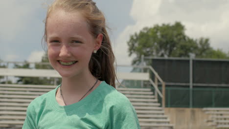 young teen girl athlete on a track smiles at camera