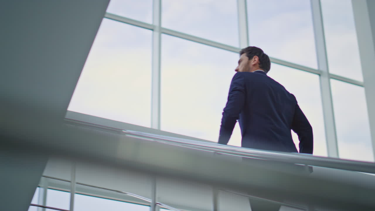 Rich man climbing stairs holding on metal railings. Stylish executive walking
