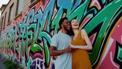 a joyful and affectionate couple interacts in front of a colorful graffiti wall