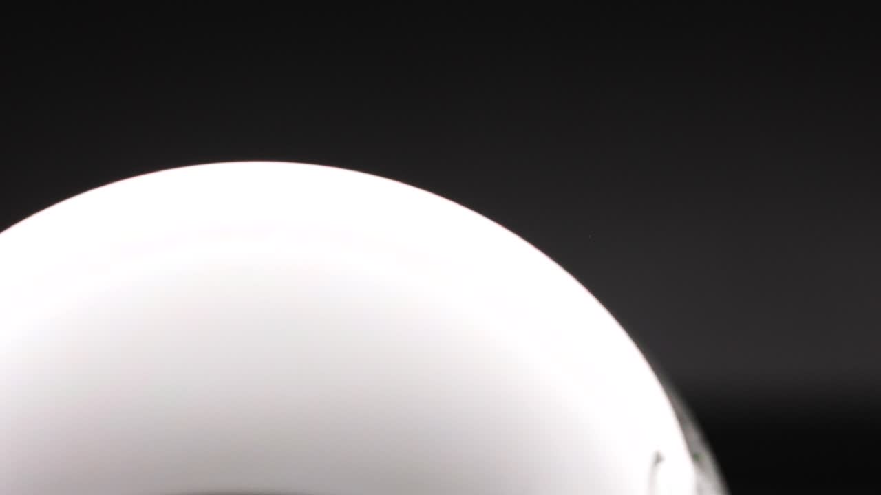 A soap bubble reflects light in a dark setting, showcasing smooth motion and subtle color changes over seven seconds