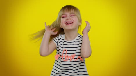 funny child girl in striped t-shirt listening music, smiling dancing to disco music, having fun