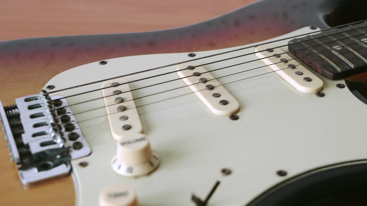 deslice el movimiento de la vieja guitarra eléctrica con un patrón fino de cuerdas de guitarra colocadas sobre una mesa de madera